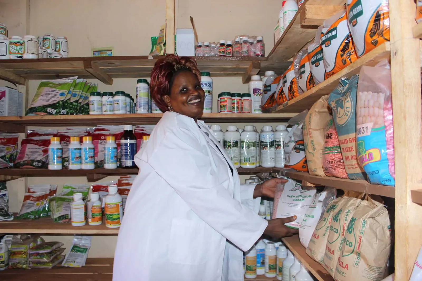 Agro-dealer in her input shop, shelves stocked with seed and crop-protection products
