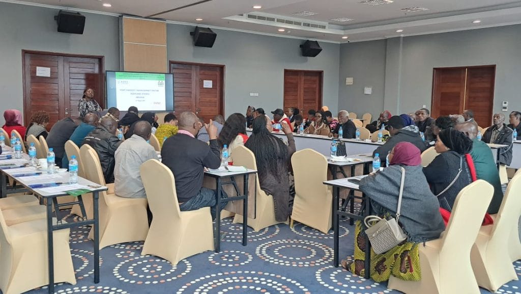 Participants in formal room attending Arusha grain traders contracts training Tanzania 2025 with presenter leading the seminar
